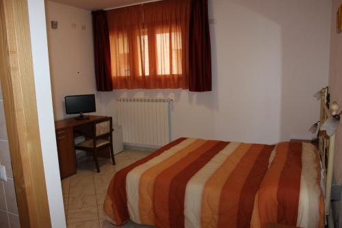 a bedroom with a bed and a desk and a television at Albergo Ristorante Pizzeria La Bocca di Bacco in Abbadia San Salvatore