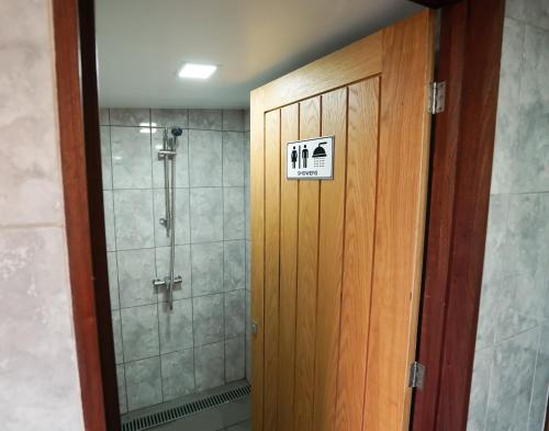 a bathroom with a shower with a sign on the door at Deluxe Glamping Pod with Hot Tub in Frodsham