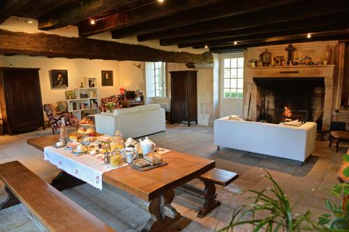 a living room with a table and a fireplace at Le prieuré Saint Barthélémy in Azay-le-Brûlé