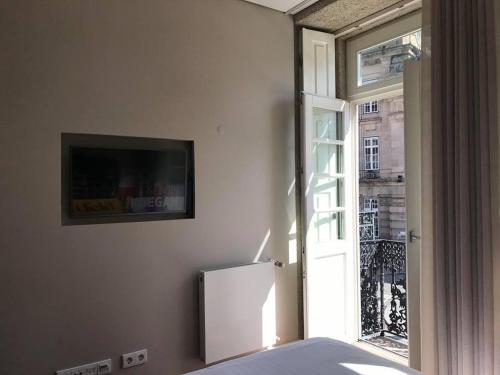 a room with a bed and a window and a tv at Apartamento Cardosas, São Bento in Porto