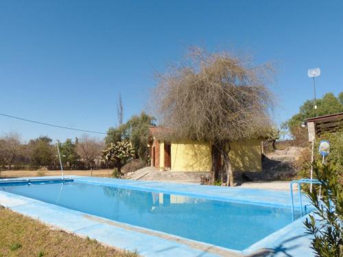 uma piscina com uma árvore ao lado de um edifício em Parador La Rosita em San Agustín de Valle Fértil