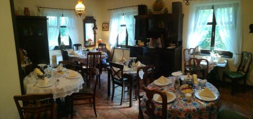 a dining room with white tables and chairs and windows at Stylowy Zajazd Pod Czarnym Kogutem in Czarna