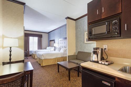 ByramにあるHoliday Inn Express Hotel & Suites Byram, an IHG Hotelのベッドとキッチン付きの小さなホテルルームです。