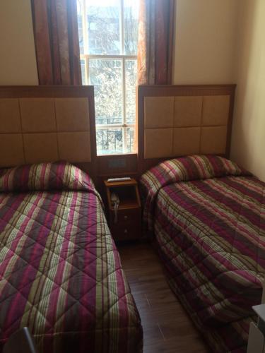 a room with two beds and a window at White House Hotel in London