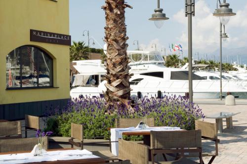 a restaurant with tables and purple flowers in front of a marina at Marina Place Resort in Genova