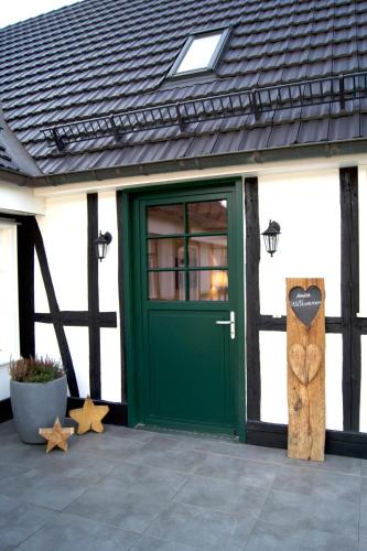 a green door on a white building with stars at Ferienwohnungen Schneider in Lennestadt