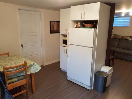 a kitchen with a white refrigerator and a table at Gite La Ptite Falaise hébergement touristique in Sainte-Anne-des-Monts