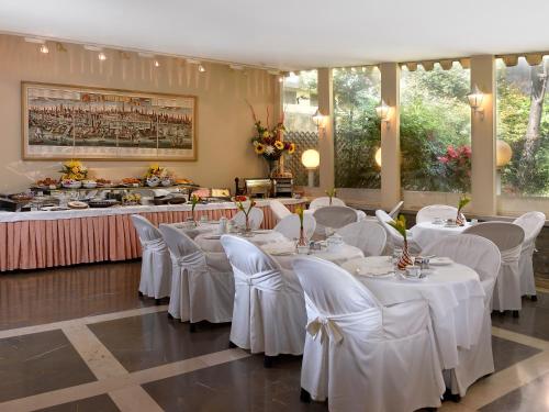 una sala da pranzo con tavoli bianchi e sedie bianche di Hotel Amadeus a Venezia