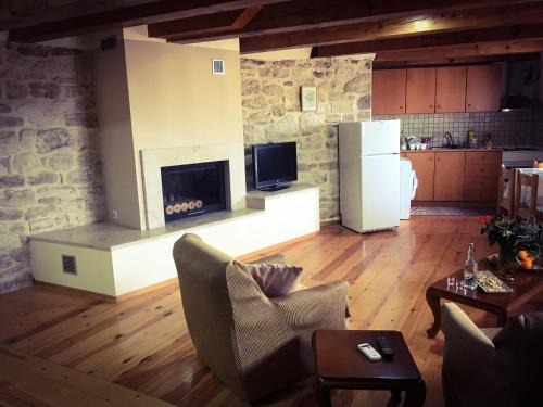 a living room with a fireplace and a kitchen at Antonia’s Home Alfa Village in Alfá