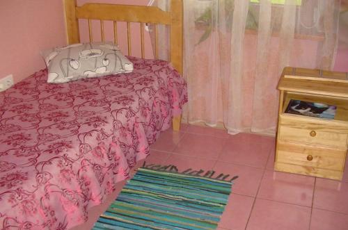 a bedroom with a pink bed and a wooden table at Guest House Vītoli in Kolka