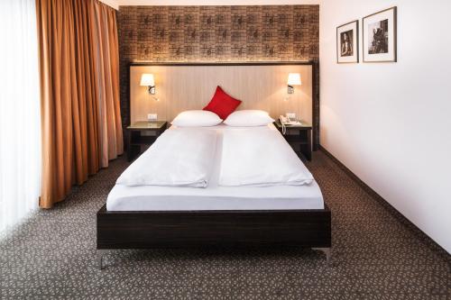 a bedroom with a large bed with red pillows at Hotel Plaza in Duisburg