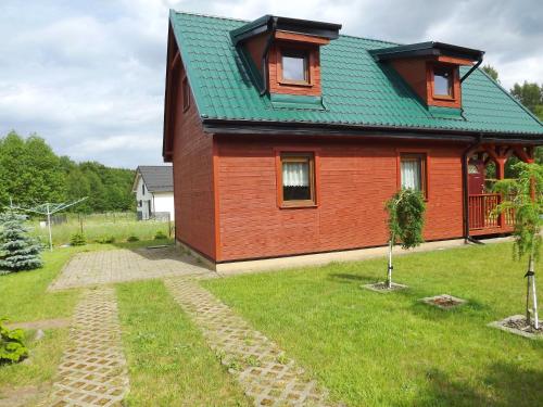 a red house with a green roof and a yard at Domek Sabrinka in Słajszewo