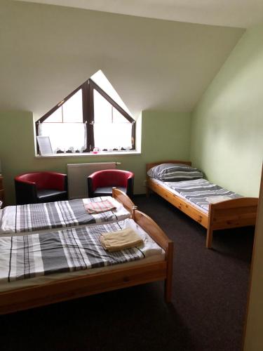 two beds in a room with a window at Penzion Tetřívek in Nové Hutě