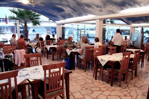 a group of people sitting at tables in a restaurant at Marina Frapa Resort Rogoznica in Rogoznica
