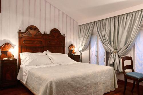 a bedroom with a bed with a wooden headboard and curtains at Residenza d'Epoca Campo Regio Relais in Siena