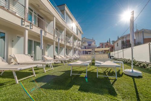 a row of lounge chairs on the grass in front of a building at Hotel Villa Katy in Bardolino