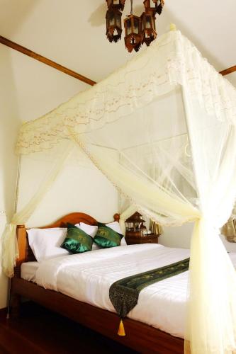 a bedroom with a white canopy bed with pillows at Aphilapa Residence in Chiang Mai