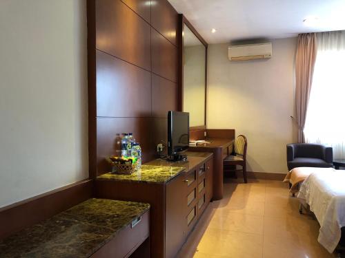 a hotel room with a bed and a desk with a television at Grand Sakura Hotel in Medan