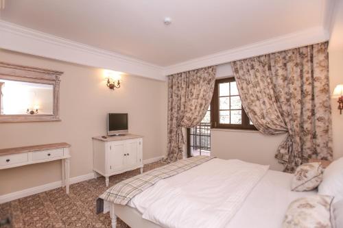 a bedroom with a white bed and a television at PENSIUNEA DIMITRIOS Relaxare cu jacuzzi pe Valea Cernei in Băile Herculane