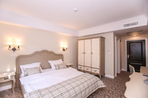 a bedroom with a white bed and a desk at PENSIUNEA DIMITRIOS Relaxare cu jacuzzi pe Valea Cernei in Băile Herculane