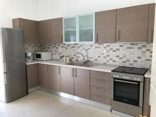 a kitchen with wooden cabinets and a stainless steel refrigerator at Villa Korais Luxury 3br apt with sea view in Thessaloniki
