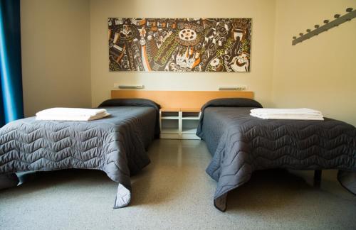 a room with two beds and a painting on the wall at Barcelona Pere Tarrés Youth Hostel in Barcelona