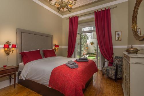 a bedroom with a large bed with red curtains and a red ottoman at Lisbon Garden Retreat in Lisbon