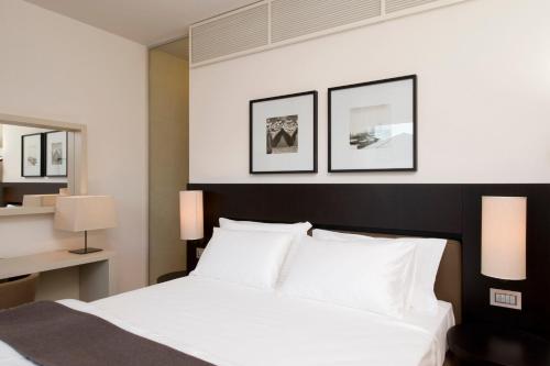 a bedroom with a white bed and three pictures on the wall at Marina Place Resort in Genova