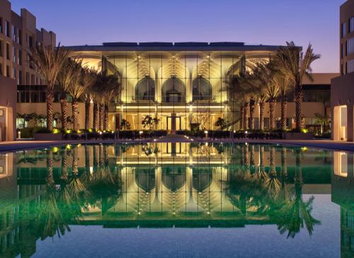 ein Gebäude mit einem Pool mit Wasser davor in der Unterkunft Kempinski Hotel Muscat in Muscat