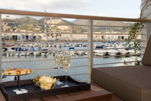a table with two wine glasses and a view of a harbor at Marina Place Resort in Genova