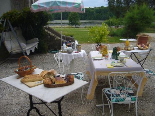 Deux tables et des chaises avec de la nourriture et un parasol dans l'établissement Château de Villeron, à Savigny-en-Revermont