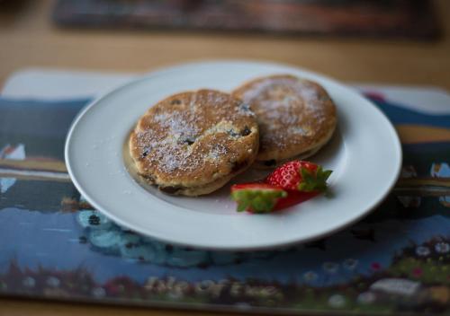 a plate with two pancakes and a strawberry on a table at Aberconwy House B&B in Betws-y-coed