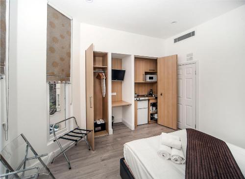 mały pokój z łóżkiem i kuchnią w obiekcie NOX Kensington w Londynie