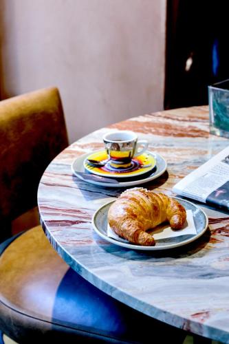 una mesa con un plato de cruasán y una taza de café en Locanda Pandenus Brera, en Milán