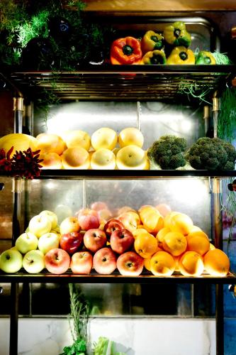 Dos estantes llenos de manzanas y otras frutas y verduras. en Locanda Pandenus Brera, en Milán