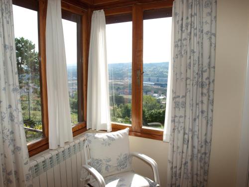 a chair sitting in a room with windows at Hotel Casa Camila in Oviedo