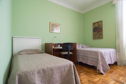 a bedroom with two beds and a desk in it at Flat Imperador in Petrópolis