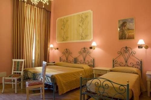 2 camas en una habitación con paredes de color naranja en Hotel Principi D'Acaja, en Turín