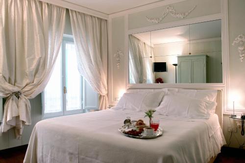 Una cama blanca con un plato de comida. en Residenza d'Epoca Campo Regio Relais, en Siena