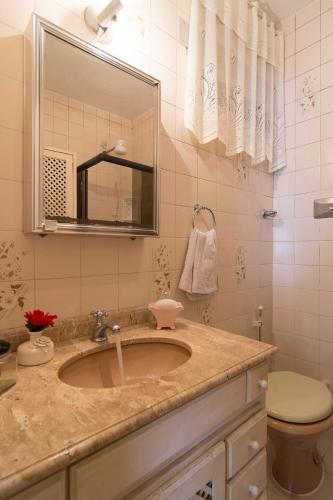a bathroom with a sink and a toilet and a mirror at Flat Imperador in Petrópolis