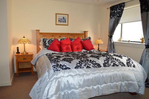 a bedroom with a black and white bed with red pillows at Queens View in Dunoon