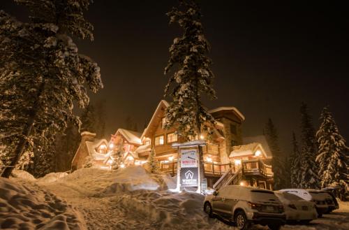 a house covered in snow at night with cars parked in front at Winston Lodge in Golden