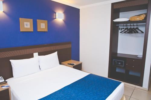 um quarto com uma cama e uma parede azul em Comfort Hotel Araraquara em Araraquara