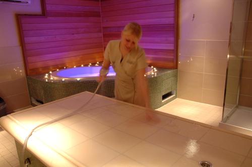 a woman standing in a bathroom with a tub at Knights Hill Hotel & Spa in Kings Lynn