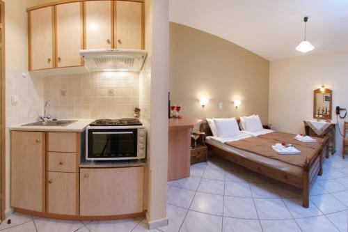 a room with a bed and a kitchen with a microwave at Katerina Studios in Ayia Evfimia