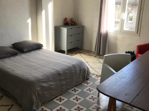 sypialnia z łóżkiem, stołem i komodą w obiekcie Appartement à Arles w mieście Arles