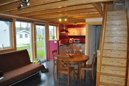eine Küche und ein Esszimmer mit einem Tisch in einem winzigen Haus in der Unterkunft Bungalow in Froidchapelle
