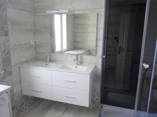 bagno bianco con lavandino e specchio di Le gîte du forgeron a Trélévern