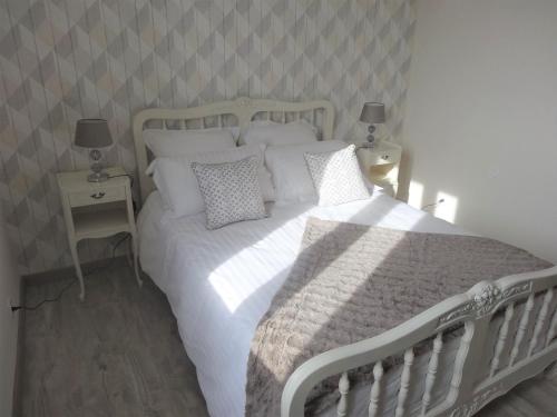 um quarto com uma cama branca com almofadas e 2 candeeiros em Le gîte du forgeron em Trélévern