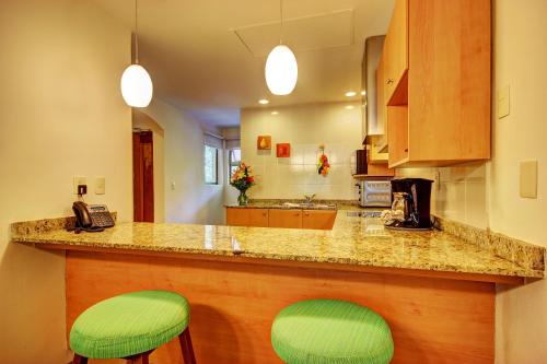 a kitchen with two green stools at a counter at Riviera Maya Suites in Playa del Carmen